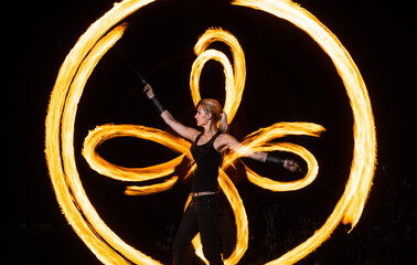 Kick off the holiday season. Sexy woman perform fire tricks in darkness. Fire performance. Burning...