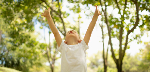 Happy little boy outdoors with arms in the air feeling free