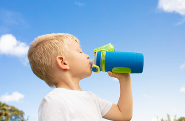 little boy drinking from bottle of water outdoors. Health and body care concept. 