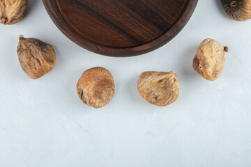 Dried tasty figs around wooden plate