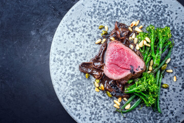 Modern style barbecue dry aged angus beef filet steak natural with broccolini and cep mushroom...