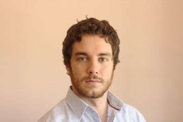 Portrait of an handsome young man with gray eyes, beard and brown hair.