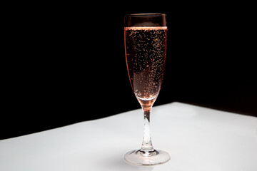 A glass of pink champagne on the table. Black-white background. Champagne for the holiday