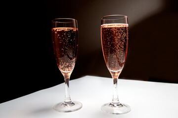 Two glasses of pink champagne on the table. Black-white background. Champagne for the holiday