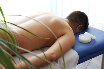 Man lying prone down on a masseur's table