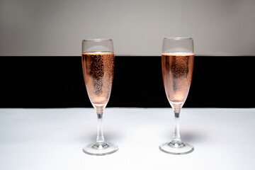 Two glasses of pink champagne on the table. Black-white background. Champagne for the holiday
