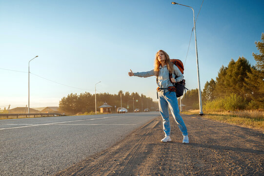 Travel woman with backpack hitchhiking on road