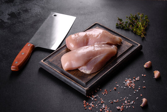 Fresh chicken fillet on a dark concrete table with spices and herbs