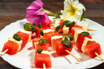 watermelon canapes with cheese sprinkled with mint on a plate