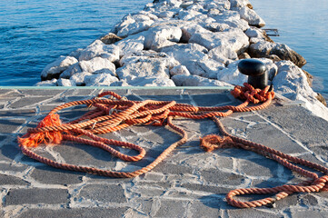 Focus on a bitt with ropes on the wharf. 