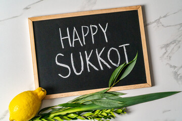 inscription Happy Sukkot, Lulav and Etrog on chalkboard.