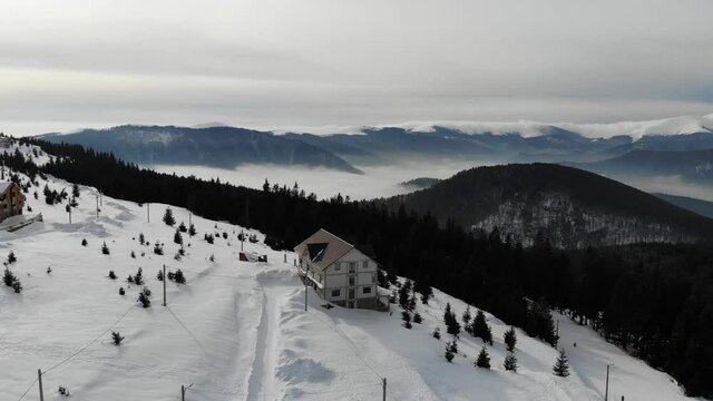 Aerial view of Retezat Mountains in the Carpathians covered with snow and a sea of clouds over the mountain valley
