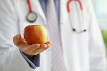 Male medicine therapeutist doctor hands holding red fresh ripe apple