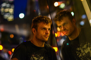 Man looking at mirror image reflection on glass
