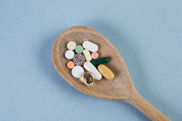 Fototapeta na wymiar Pills, tablet, capsule and vitamin in wood spoon on blue background, medicine and drug concept.