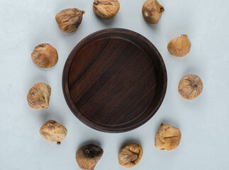 Dried tasty figs around wooden plate