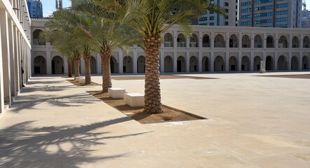 Inneres Fort von Qasr Al Hosn mit zweistöckigem Bogengang und Palmen im Vordergrund