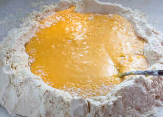 Homemade pasta, raw chicken eggs and  flour  whipped on a white background.
