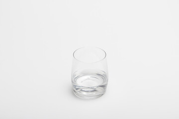The half full glass of pure water isolated on a white background. A drinking glass half filled with water. A half empty glass with water.