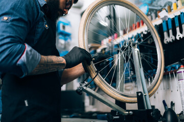 Fototapeta na wymiar Young beard bicycle mechanic repairing bicycles in a workshop..