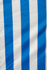Crumpled blue and white striped backdrop made of material. Street tent or stall outdoors.