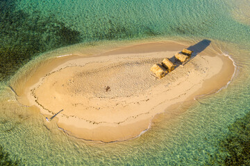 Aerial view of an isolated desert island with beach huts.