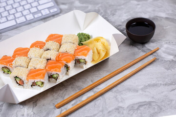 Assorted sushi and rolls near the computer keyboard.