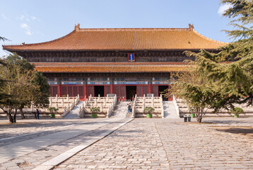 Beijing, China - April 28, 2010: Ming Tombs Changling. Wide cement path leads to double-roofed, sculpted great hall under blue sky. Green foliage on sides.