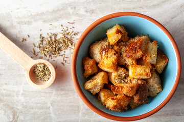 Close up flat lay image of home made croutons in a bowl. Bread cubes were baked to crisp in oven and dipped into olive oil or butter and finished with Italian seasoning. Used as a versatile garnish.