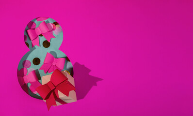 Paper art Eight number cut of bright pink paper against the turquoise background fulfilled by confetti, bows and one gif box.