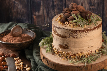 Delicious naked chocolate and hazelnuts cake on table rustic wood kitchen countertop.
