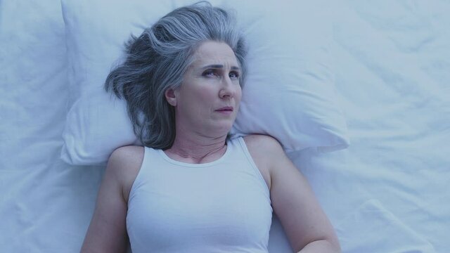 Tired Unhappy Aged Woman Lying In Bed Trying To Fall Asleep, Suffering Insomnia