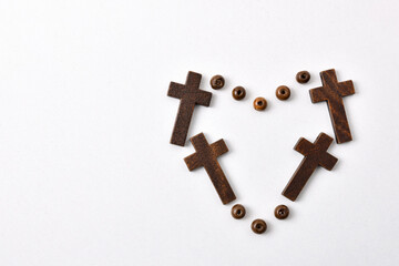 Heart made with crosses and beads on table white background