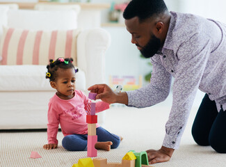 africam american family, father and daughter playing with colorful wooden blocks at home