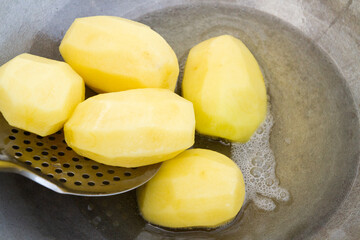 Golden potatoes are fried in boiling oil in a cauldron