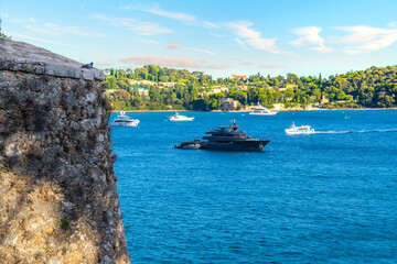 A single pigeon enjoys the view from the castle fort at Villefranche-Sur-Mer, France, of the Mediterranean sea, hillls and luxury yachts in the water.
