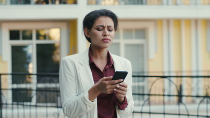 Fototapeta na wymiar Sad woman reading phone outdoors. Business woman receiving bad news at street