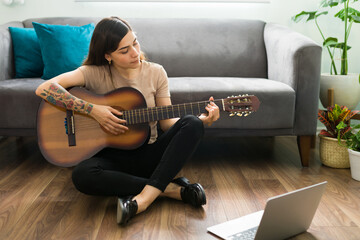 Adult woman in her 20s learning to play the acoustic guitar