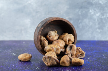 Fototapeta na wymiar Bowl of dried figs on blue background