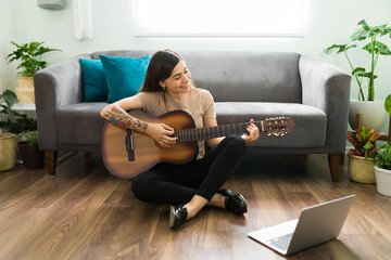 Hispanic woman practicing a new song on the guitar