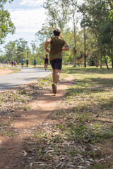 Fototapeta premium Hombre joven corriendo en sendero de arena de ñu guazu luque asunción al medio día con mucho calor entre sombras de atras