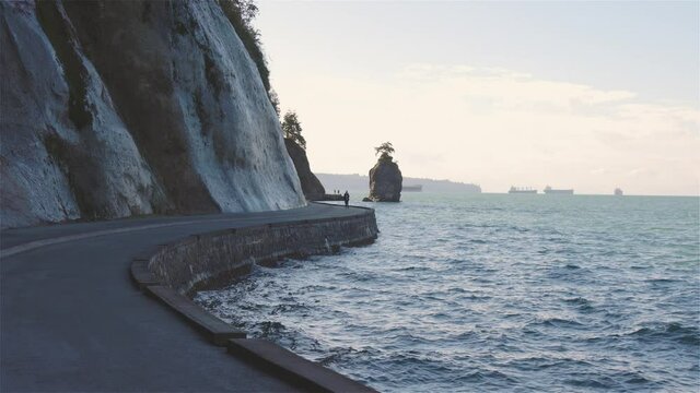 Seawall in Stanley Park and the famous Siwash Rock during a sunny winter day. Picture taken in Downtown Vancouver, British Columbia, Canada. Slow Motion