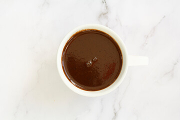 Top view of white cup with hot chocolate on marble background