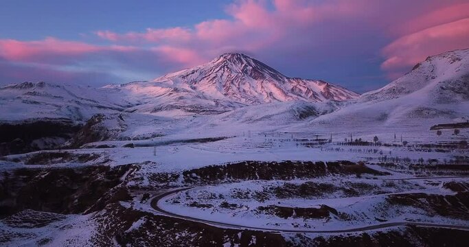 Pink Sunrise Sunset time in winter and landscape of damavand volcano in iran covered by snow in a freezing cold day in mazandaran iran. blue sky with white clouds is amazing.