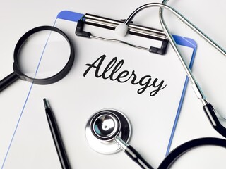Medical and health concept. Phrase ALLERGY written on paper clipboard with stethoscope,magnifying glass and a pen. 