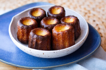 A plate of Canelés de Bordeaux with a blue napkin from the side
