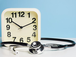 Selective focus alarm clock with stethoscope isolated on blue background. Medical and time concept.