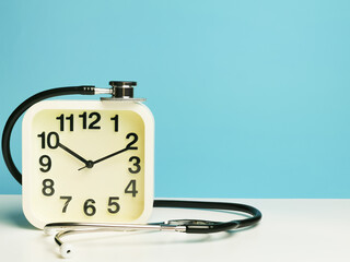 Selective focus alarm clock with stethoscope isolated on blue background. Medical and time concept.