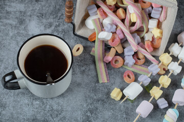 Marshmallows on wooden sticks to be grilled with a cup of drink aside