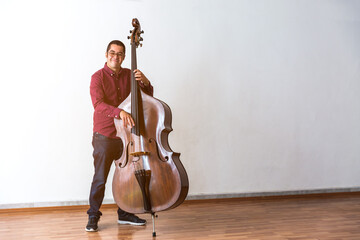 Professional double bass player. Photo shooting in studio. White background
